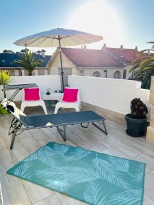 a patio with a table and two chairs and an umbrella at Acogedora casa recién reformada con jardín y wifi in Laredo
