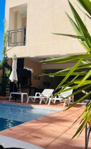 una casa con piscina y dos sillas y una sombrilla en Colibrí Apart, en Puerto Iguazú