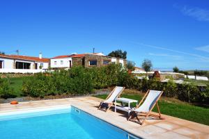a couple of chairs sitting next to a swimming pool at Casa dos Castelejos in Guerreiro