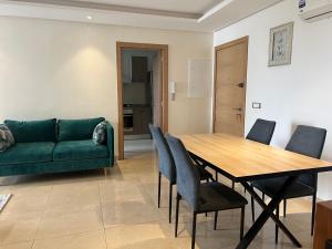 a living room with a green couch and a table and chairs at Plage des Nations Prestigia Vue sur mer in Sidi Bouqnadel