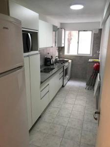 a kitchen with white appliances and a tile floor at Departamento de categoría in Ramos Mejía