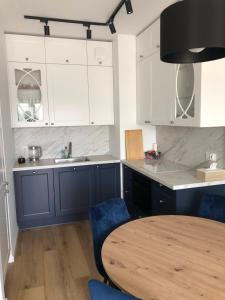 a kitchen with blue cabinets and a wooden table at Baltic Porto Wyspa Sobieszewska - Rowery i Taras in Gdańsk