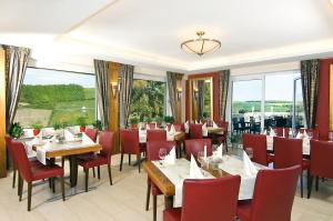 a restaurant with tables and chairs and large windows at Burg-Hotel in Obermoschel