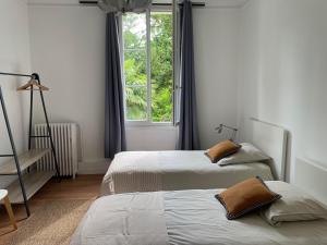 Dos camas en una habitación con ventana. en La Feuilleraie, en Tours