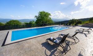 a swimming pool with two lawn chairs next to it at Villa Wild Rose in Imotski