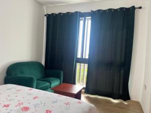 a bedroom with a green chair and a window at Plage des Nations Prestigia Vue sur mer in Sidi Bouqnadel