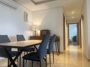 a dining room with a wooden table and blue chairs at Plage des Nations Prestigia Vue sur mer in Sidi Bouqnadel
