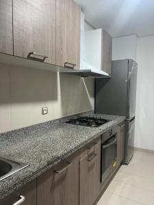 a kitchen with wooden cabinets and a stove top oven at Plage des Nations Prestigia Vue sur mer in Sidi Bouqnadel