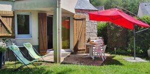 a patio with a red umbrella and chairs and a table at Cottage du Golf en Morbihan in Ploemel