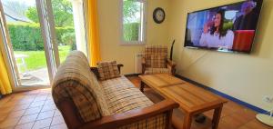 a living room with two couches and a tv at Cottage du Golf en Morbihan in Ploemel