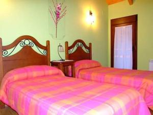 Dos camas en una habitación con rosa y púrpura en Casa Carpintero, en Torla