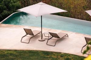 deux chaises et un parasol à côté d'une piscine dans l'établissement Armadillo Living Villas, à Zihuatanejo