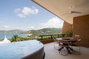 - un balcon avec une piscine, une table et des chaises dans l'établissement Armadillo Living Villas, à Zihuatanejo