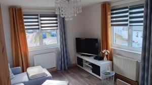 ein Wohnzimmer mit einem TV und 2 Fenstern in der Unterkunft Ferienwohnung Saalfeld - Sommerfrische Burkersdorf in Saalfeld