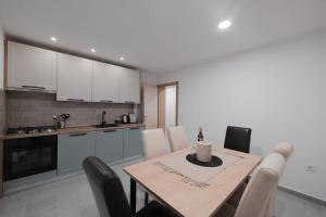 a kitchen with a wooden table and white cabinets at Apartmani Vinea Zara in Brčevec