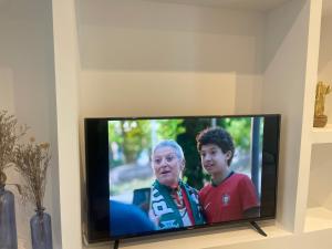 a television with a woman and a child on it at Casa da Grota do Bravo in Nordeste