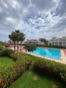 萨伊迪耶Marina Ap2的一座种满鲜花和棕榈树的度假村内的游泳池