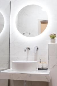a white bathroom with a sink and a mirror at Paralia Luxury Apartment in Paralia Katerinis