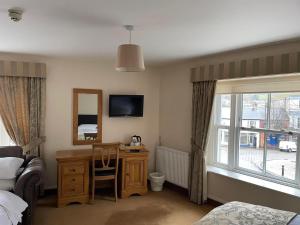 a bedroom with a desk and a bed and a window at The Cambrian Bar & Grill in Tredegar