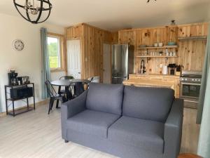 a living room with a couch and a kitchen at Le Camp Perché #1 in La Malbaie