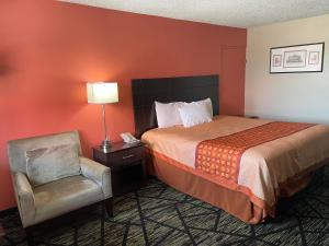 a hotel room with a bed and a chair at Travelers Lodge Beatrice in Beatrice +30 photos