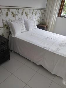 un lit avec des draps blancs et des oreillers dans une chambre dans l'établissement Village Lagoa do Forte, à Mata de São João