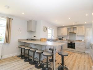a kitchen with a large island with bar stools at Llwyn Eithin in Benllech