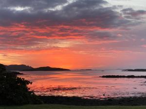 a sunset over a body of water with the sky at Bunessan Inn in Bunessan