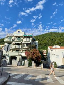 Una donna che attraversa una strada davanti a un edificio di Sea breeze Budva a Budua