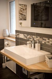 a bathroom with a white sink on a wooden counter at Moderne Wohnung zum Wohlfühlen in Brachbach