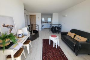 a living room with a black couch and a table at Le Cabanon, pieds dans l'eau, vue exceptionnelle in Fréjus