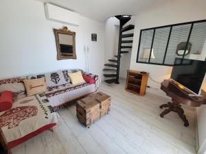 a living room with a couch and a flat screen tv at Le Cabanon, pieds dans l'eau, vue exceptionnelle in Fréjus