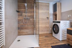 a shower in a bathroom with a washing machine at Chalet Hildegard in Pfronten +5 photos