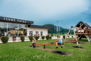 two children sitting on a bench in front of a building at Superior Holiday Home Fortuna in Čatež ob Savi +28 photos