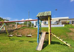 een speeltuin met een glijbaan in een tuin bij Mirante Mar de Minas - Casa para Temporada Lago de Furnas pertinho dos Canyons in São José da Barra