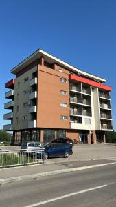 a building with cars parked in a parking lot at Apartman Nora in Teslić