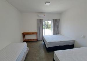 een kamer met twee bedden en een raam bij Mirante Mar de Minas - Casa para Temporada Lago de Furnas pertinho dos Canyons in São José da Barra +42 foto's