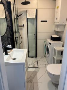 a bathroom with a sink and a washing machine at Nadmorski czas Darłówko in Darłowo +20 photos