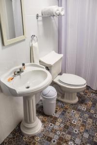 a white bathroom with a toilet and a sink at M&uacute;cara hotel in Veracruz