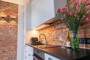 a kitchen with a brick wall and a counter with flowers in a vase at Studio Olesińska in Warsaw