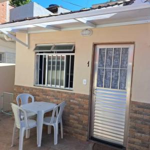 a white table and chairs in front of a house at Suítes do Jajá 900m da Praia do Forte Centro de CF in Cabo Frio