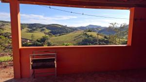 een raam in een rode kamer met uitzicht op de bergen bij Sítio Ramos casa da montanha in Cunha