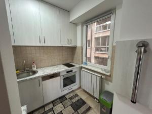 a kitchen with white cabinets and a sink and a window at Belma's Apartment in Sarajevo +8 photos