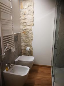 a bathroom with a toilet and a sink and a stone wall at casa del corso 27 in Sirolo