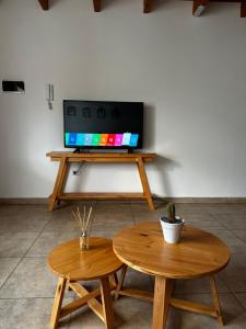 sala de estar con 2 mesas y TV de pantalla plana en Departamento Mallin Azul, en El Bolsón