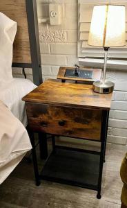 a table with a lamp on it next to a bed at Downtown Cottage Hammond, Pool, Hot Tub, King Bed in Hammond