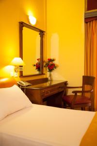 a bedroom with a bed and a desk with a mirror at Galini Palace in Athens