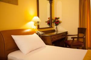 a hotel room with a bed and a desk with a mirror at Galini Palace in Athens