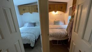 a bedroom with two beds and a door leading into a room at SAYANG26 gezellige gezinsvriendelijke stacaravan op familiecamping De Vossenburcht in natuurgebied Reestdal - no workers allowed in IJhorst +52 photos