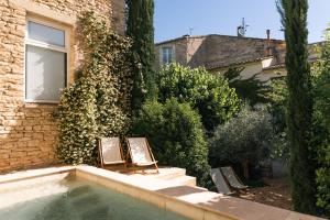 two chairs sitting next to a building with a swimming pool at Le Clos de Gordes in Gordes